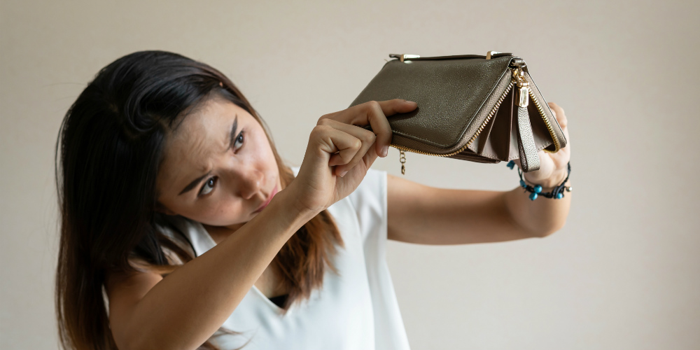 girl looking at a wallet with no money