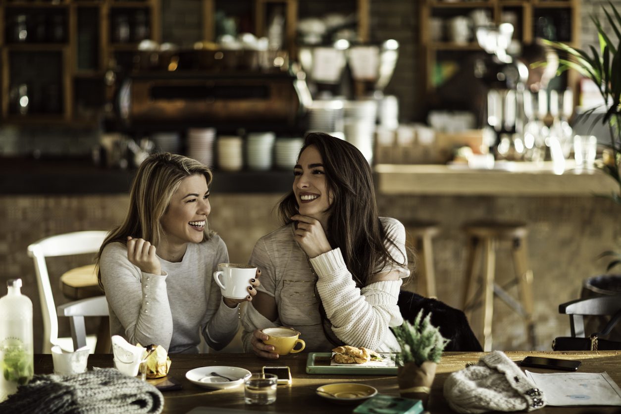 two women drinking coffee and laughing